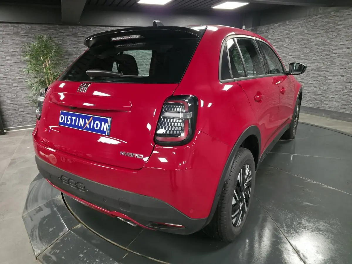 Vue 3/4 arrière droite d'une FIAT 600 rouge hybride 2024 avec feux arrière LED et jantes bicolores.