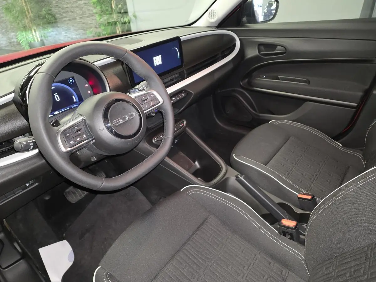 Intérieur avant de la FIAT 600 rouge 2024, vue côté conducteur avec tableau de bord numérique et volant Soft-Touch.