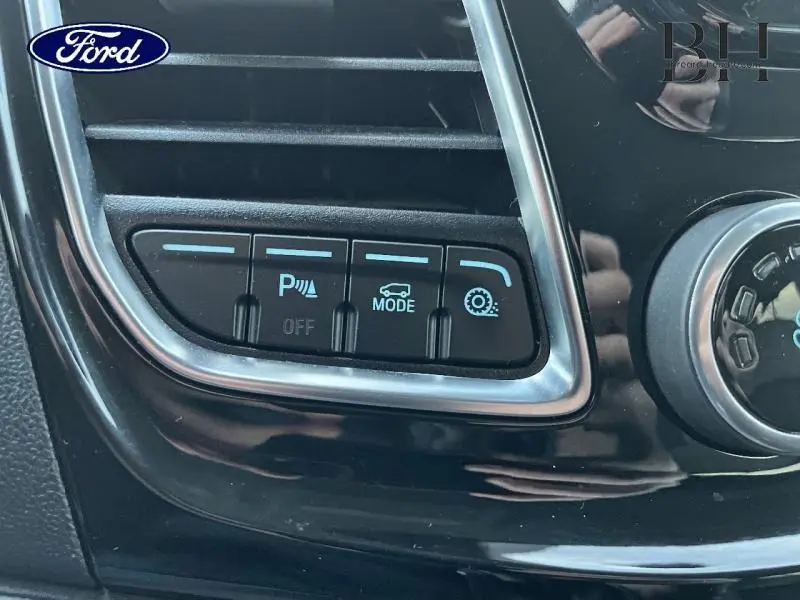 Gros plan sur les boutons de commande du tableau de bord du Ford Transit Custom Fourgon bleu azur, avec fonction parking et mode conduite.