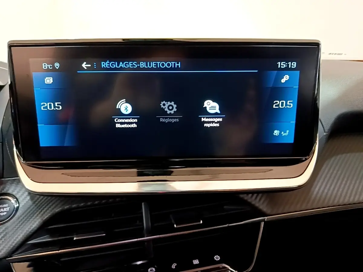 Écran tactile central du tableau de bord du Peugeot 2008 orange, affichant les réglages Bluetooth et la température à 20,5°C.