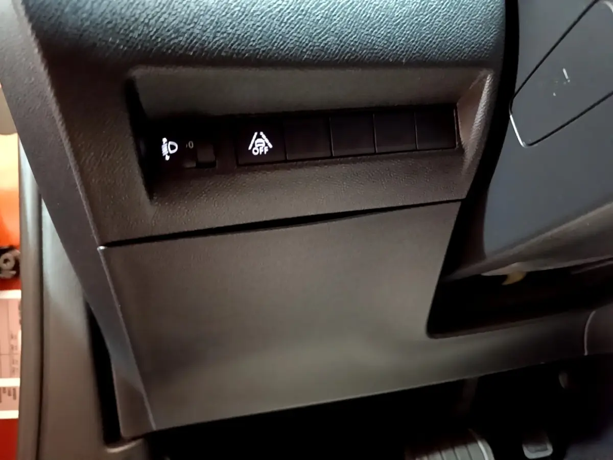 Détail du tableau de bord côté gauche avec commandes de réglage des phares et assistance au maintien de voie, intérieur noir.