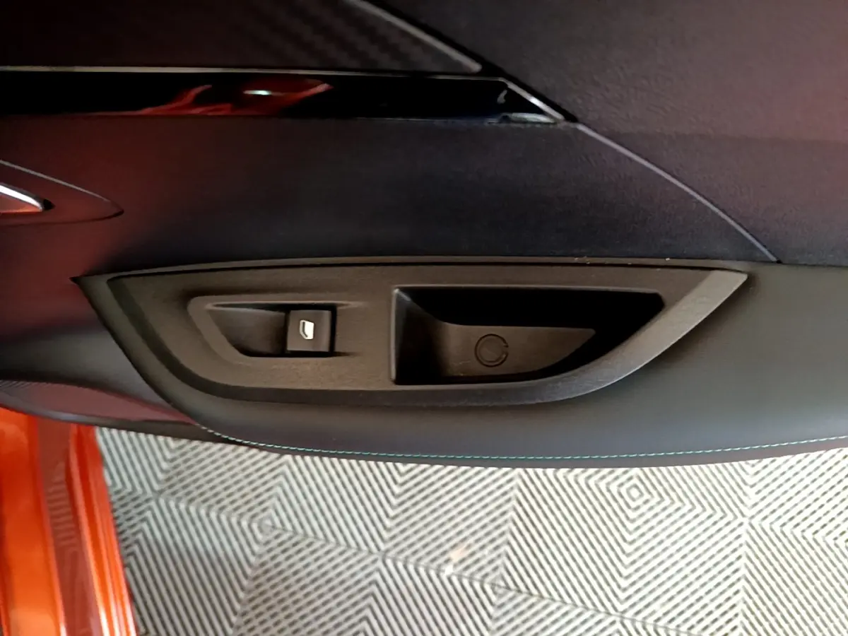 Détail de la poignée intérieure de porte côté gauche d’un Peugeot 2008 orange, avec bouton de verrouillage.