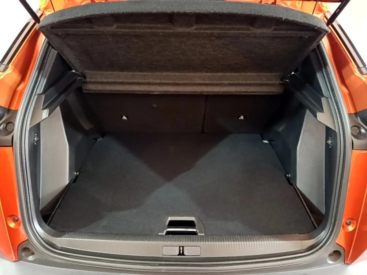 Coffre ouvert vu de l'arrière d'un Peugeot 2008 orange, montrant un espace de chargement propre et spacieux.
