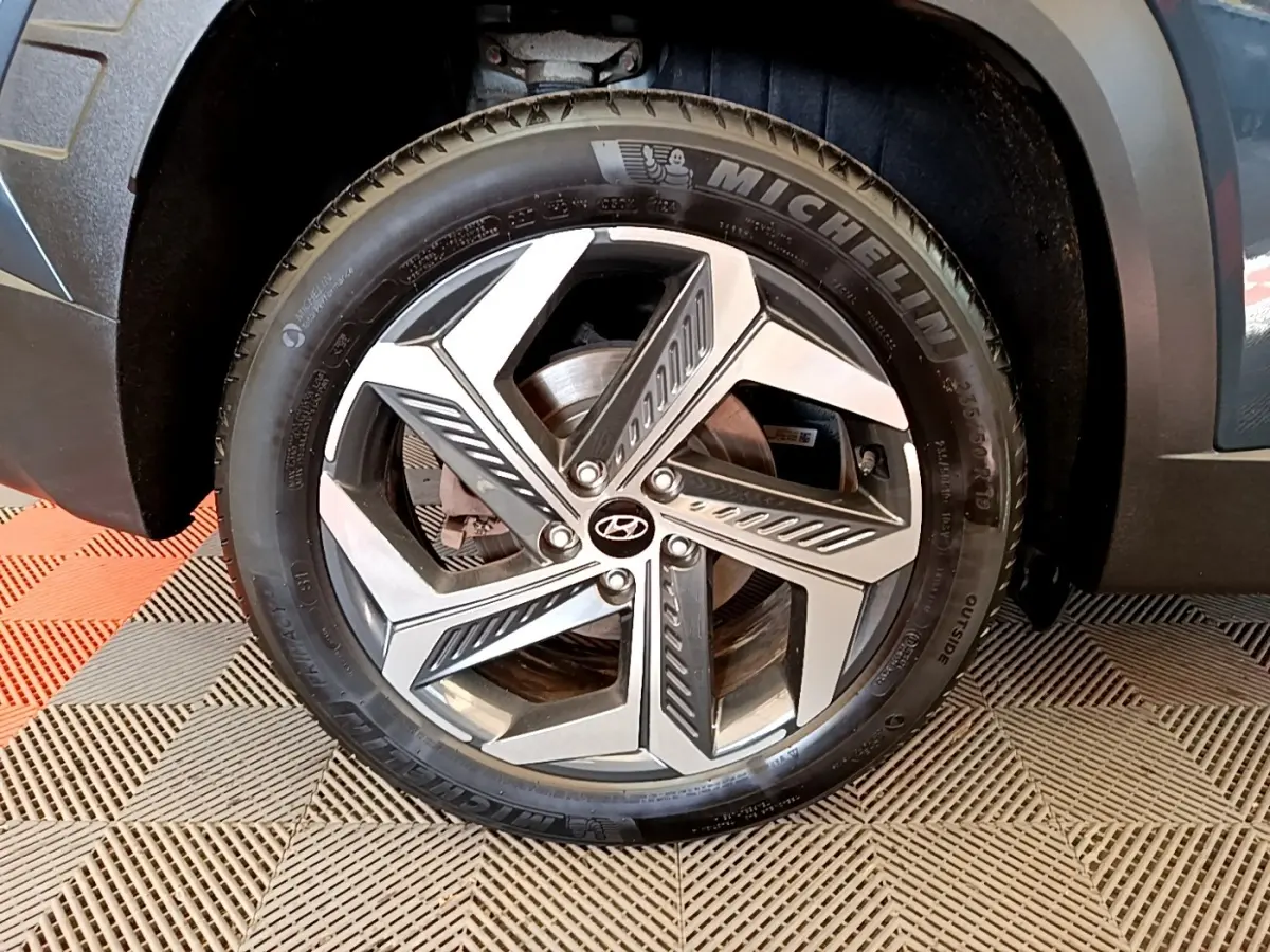 Gros plan sur la roue avant droite du Hyundai Tucson bleu, mettant en valeur la jante alliage moderne et le pneu Michelin.