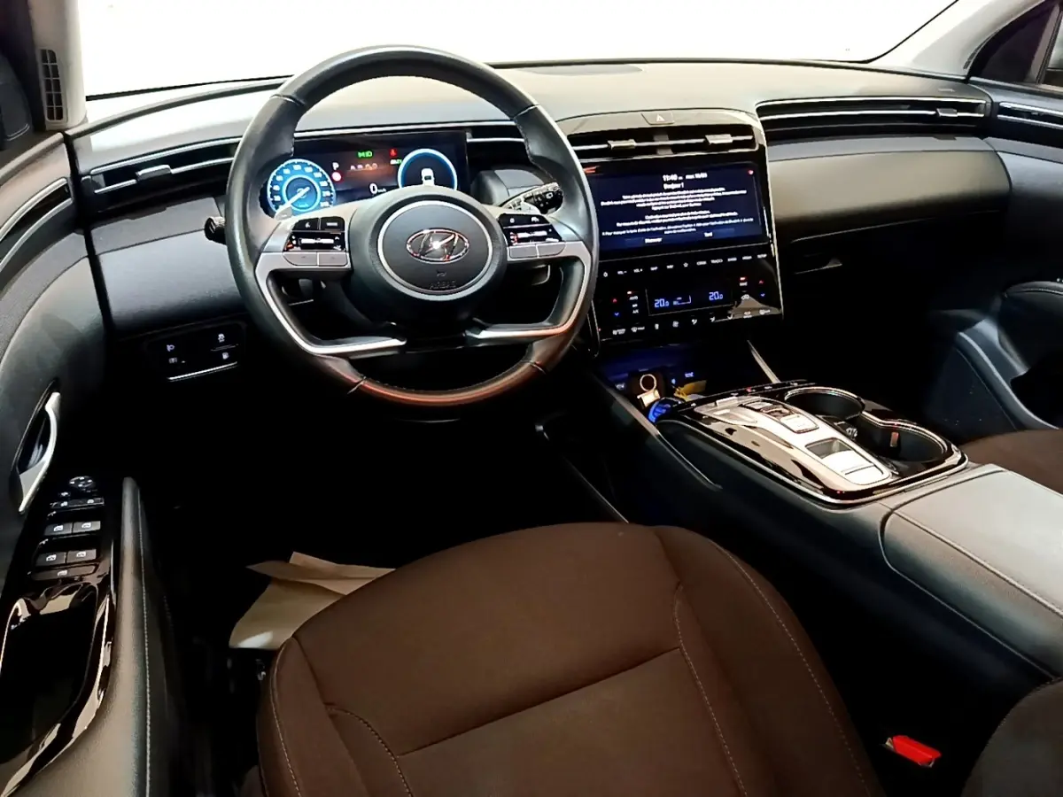 Vue intérieure avant du Hyundai Tucson 2023, tableau de bord noir avec écran tactile central et volant multifonctions.