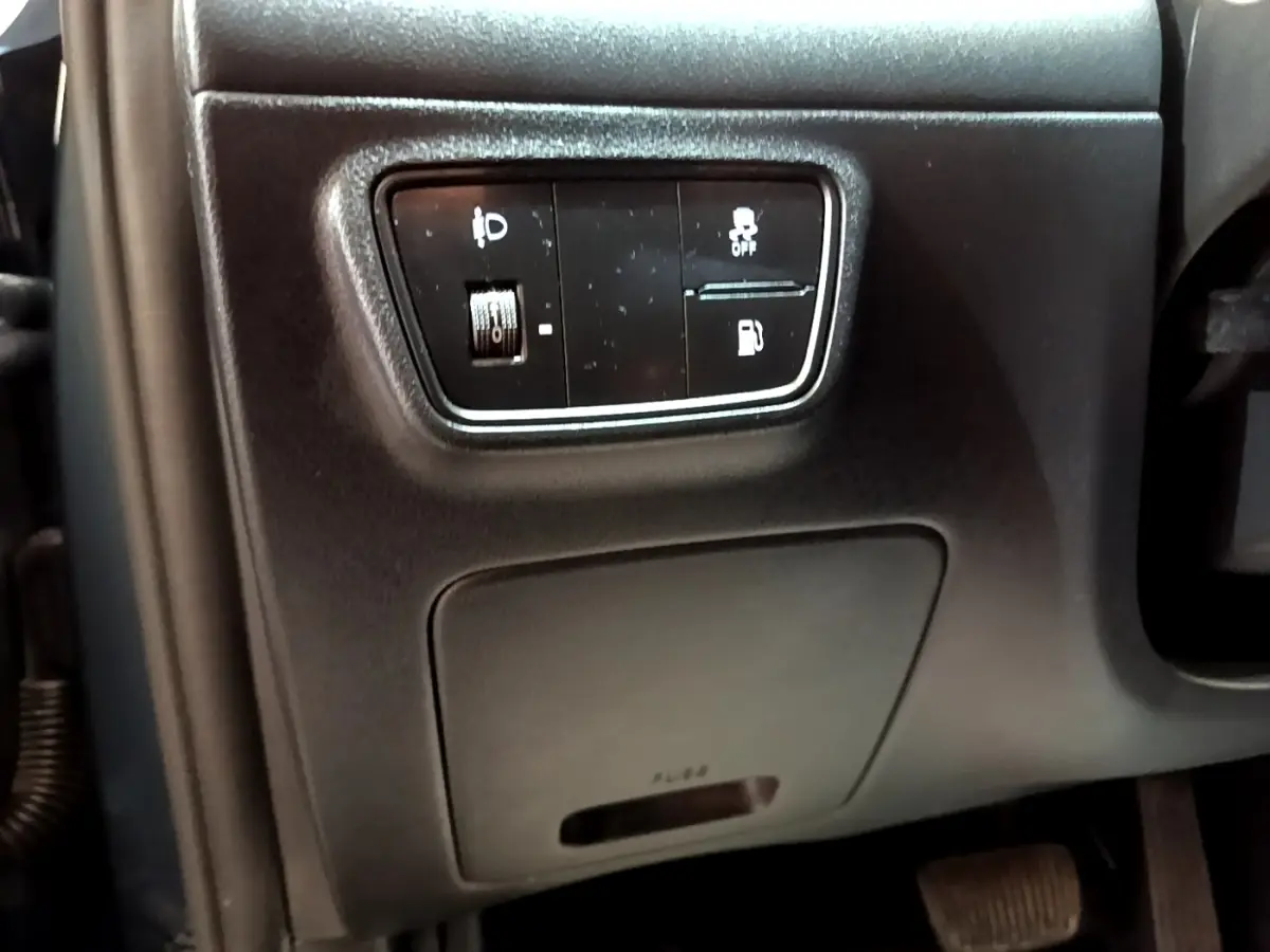 Gros plan sur les commandes noires côté gauche du tableau de bord du Hyundai Tucson 2023, avec réglage phares et traction.