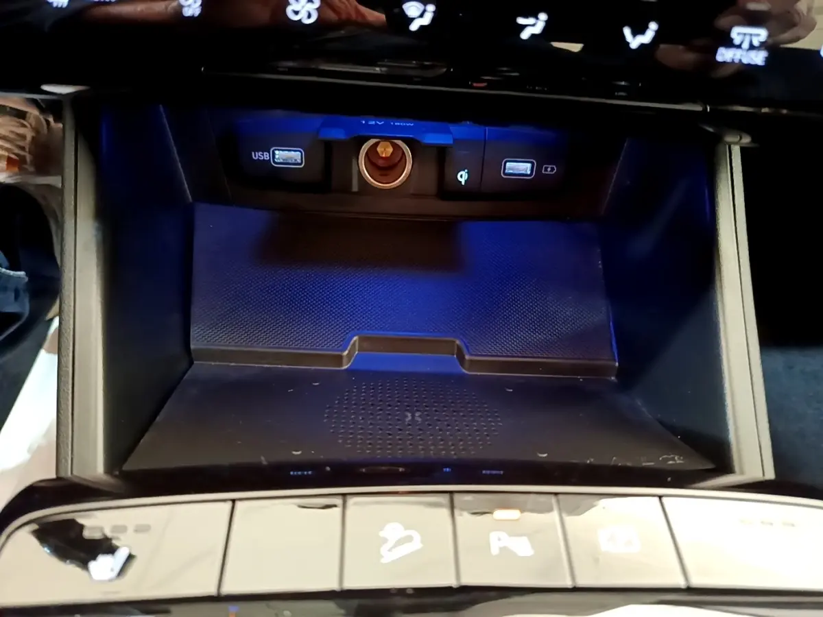 Vue rapprochée de la zone de recharge par induction et ports USB du Hyundai Tucson bleu 2023, avec boutons de commande en bas.