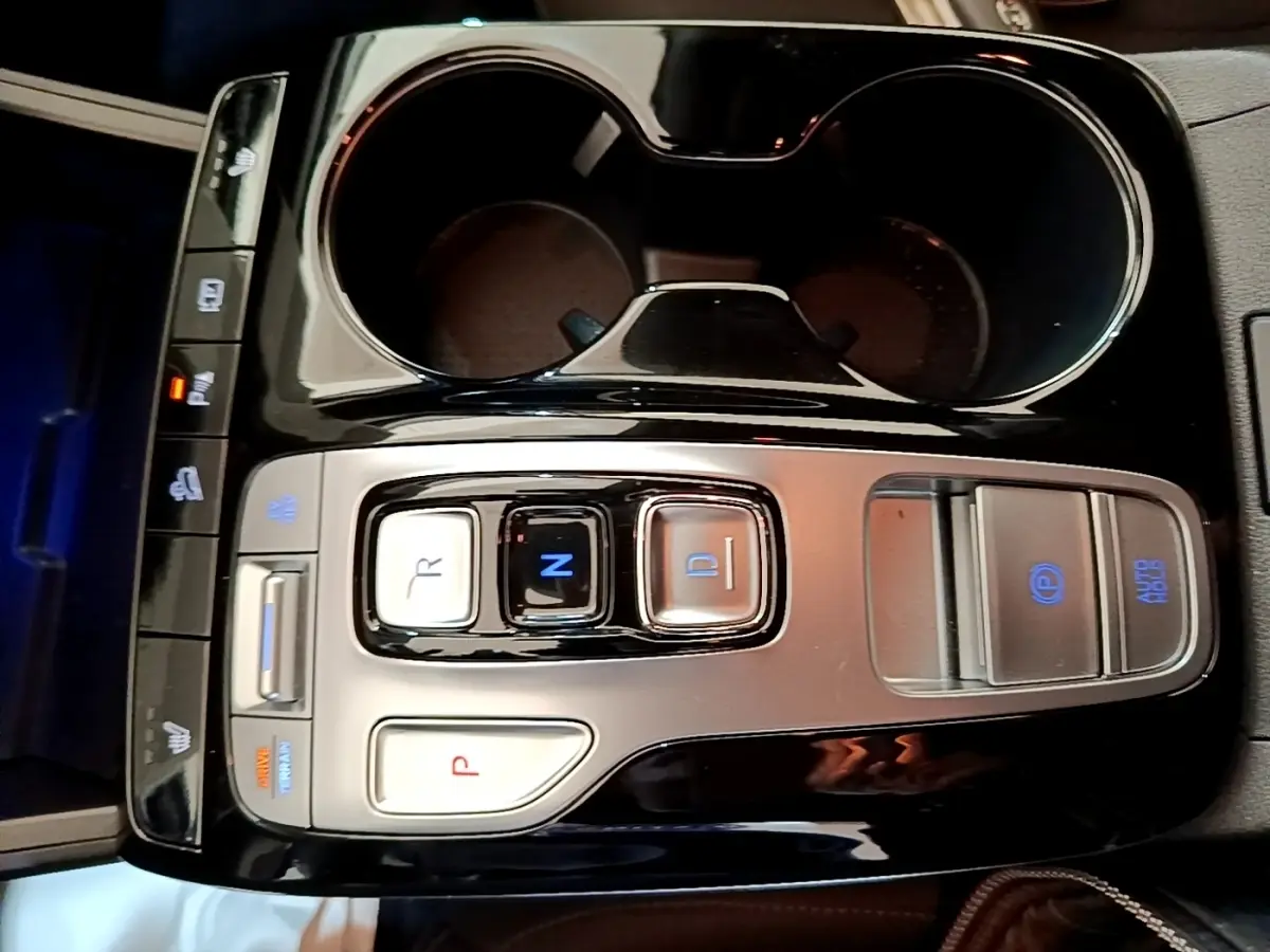 Vue rapprochée de la console centrale noire et argentée du Hyundai Tucson bleu avec commandes de boîte auto et frein électrique.