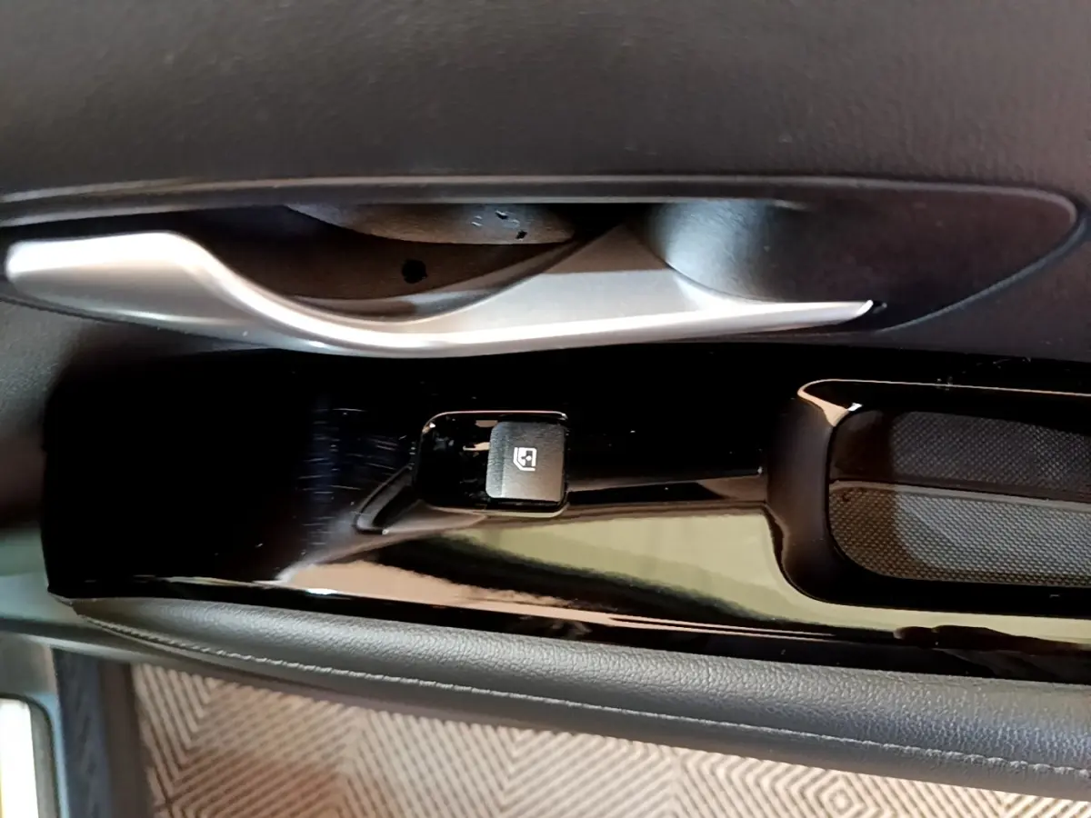 Gros plan sur la commande de lève-vitre côté conducteur du Hyundai Tucson bleu, avec poignée de porte argentée.