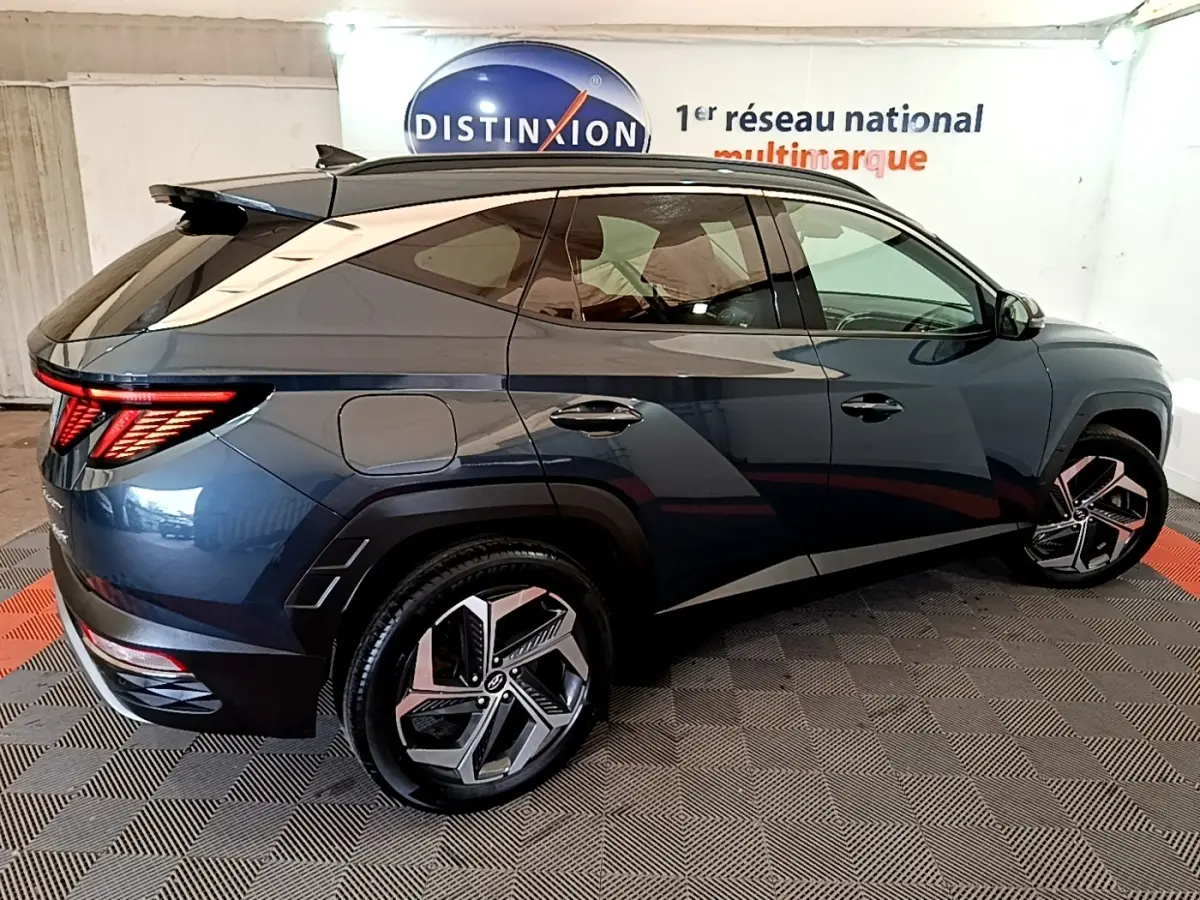 Vue 3/4 arrière droite du Hyundai Tucson bleu 2023 avec feux LED distinctifs et jantes alliage modernes.