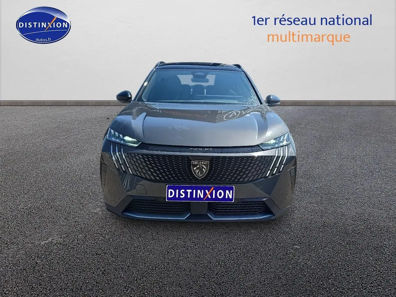 Vue frontale d'un Peugeot 5008 Hybrid 145 GT gris titane avec calandre noire et phares LED allumés