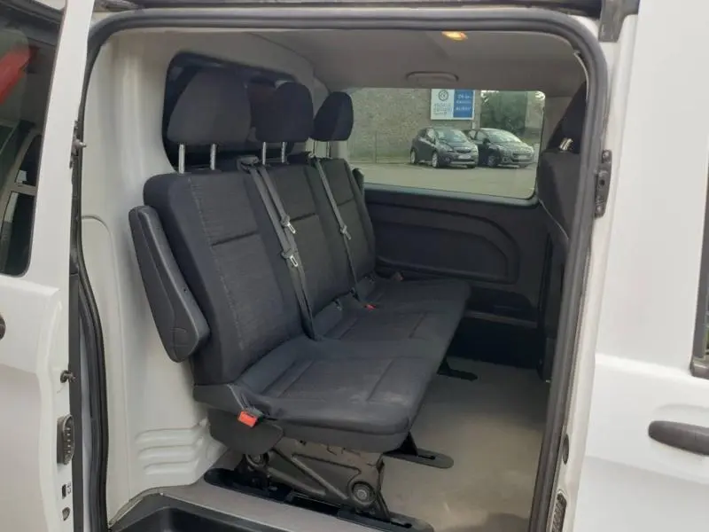 Vue intérieure côté droit du Mercedes Vito Fourgon blanc, montrant la banquette arrière noire trois places avec ceintures de sécurité.