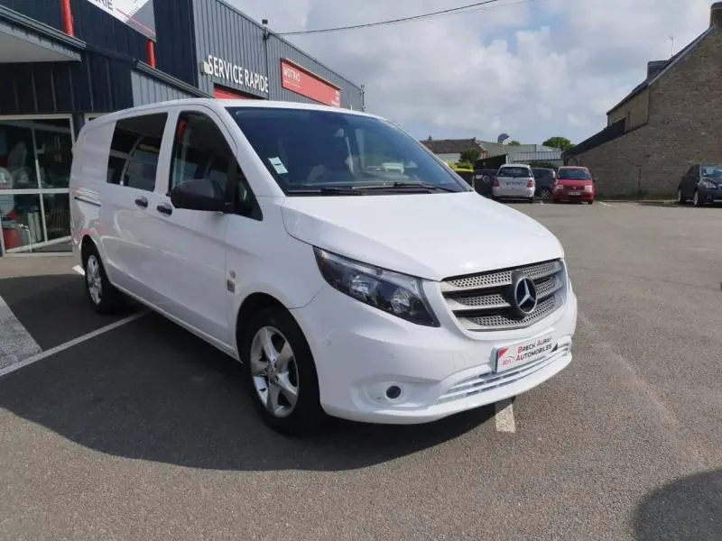 Vue 3/4 avant droite d'un Mercedes Vito Fourgon 111 CDI Mixto Long Pro E6 blanc pur stationné devant un garage.