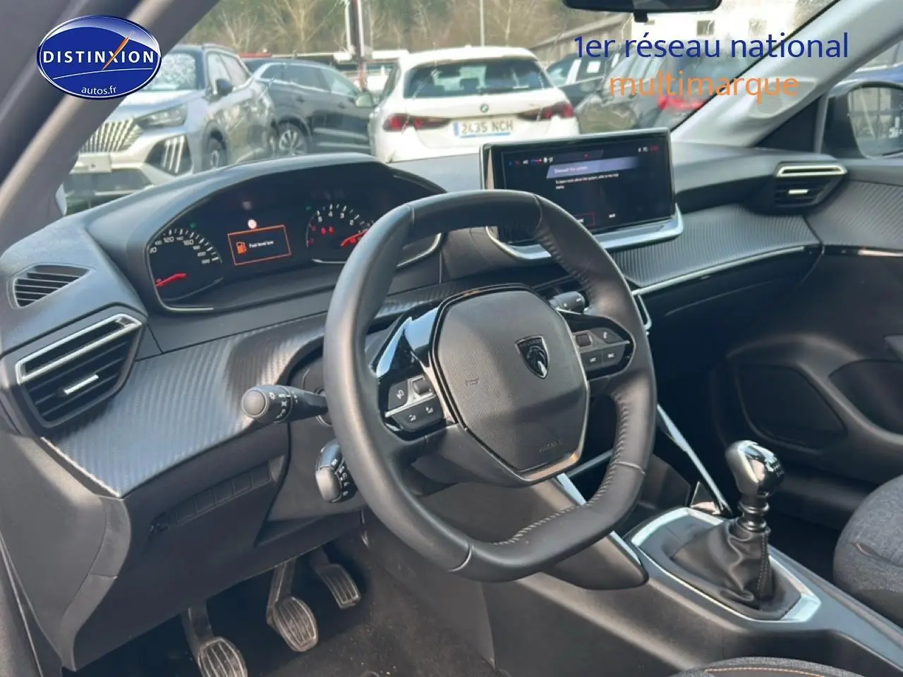 Vue intérieure côté conducteur du Peugeot 208 gris Artense, volant compact et écran tactile central visible.