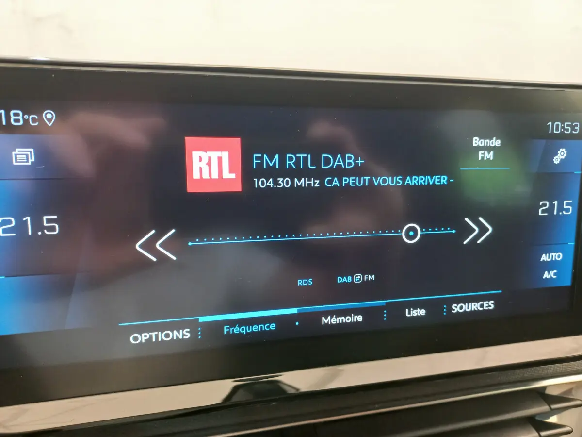 Écran tactile intérieur du Peugeot 5008 affichant la radio FM RTL à 104,3 MHz avec réglage de la climatisation à 21,5°C.