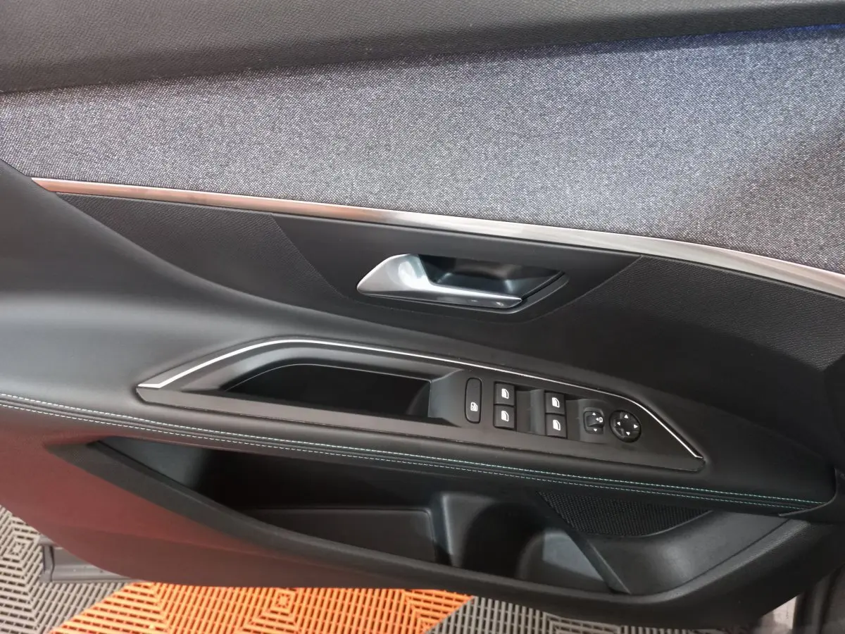 Vue rapprochée de la porte côté gauche du Peugeot 5008 gris foncé, avec commandes des vitres et poignée argentée.