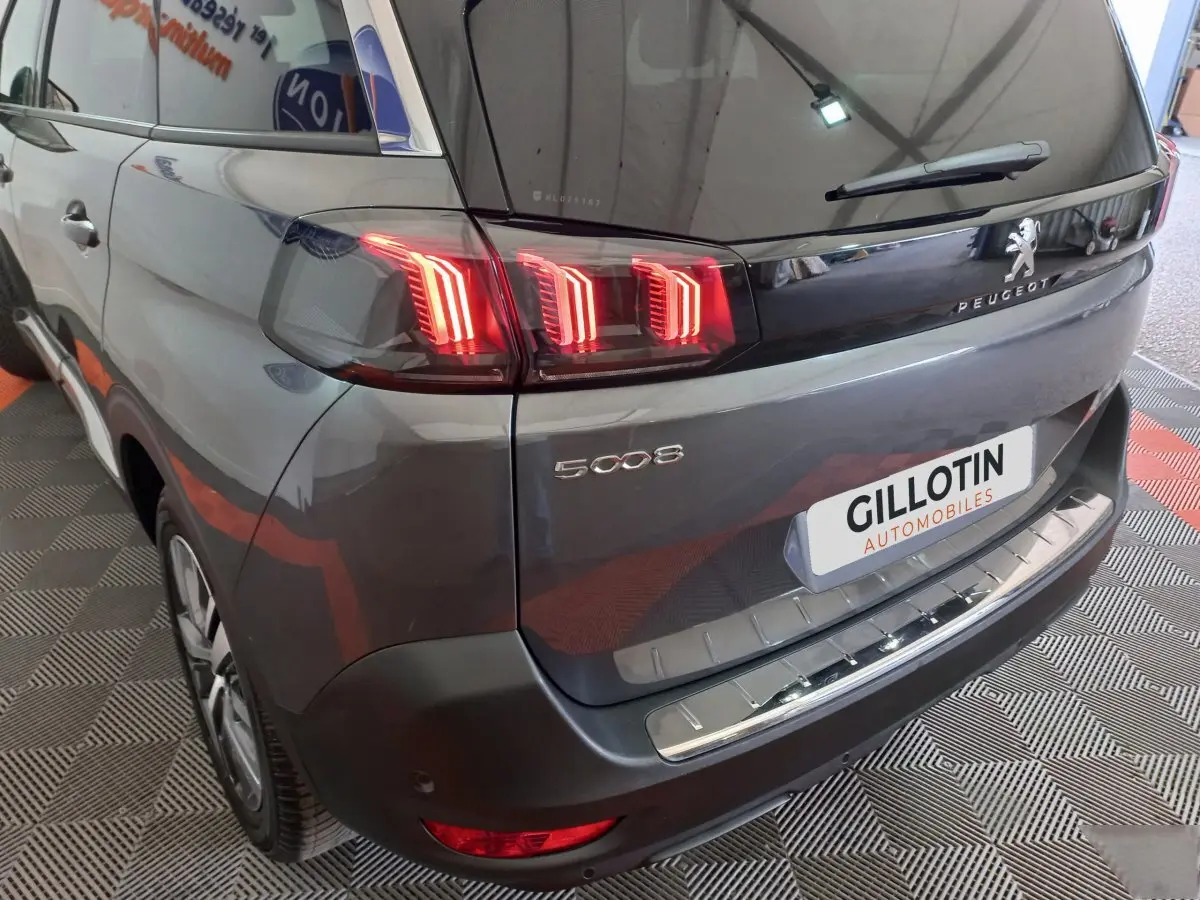 Vue 3/4 arrière gauche d’un Peugeot 5008 gris foncé avec feux arrière LED et protection de seuil de coffre en inox.