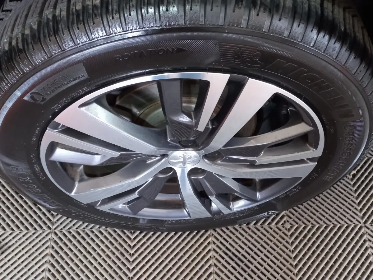 Gros plan sur la jante alliage bicolore et pneu Michelin du Peugeot 5008 gris foncé, vue de dessus.