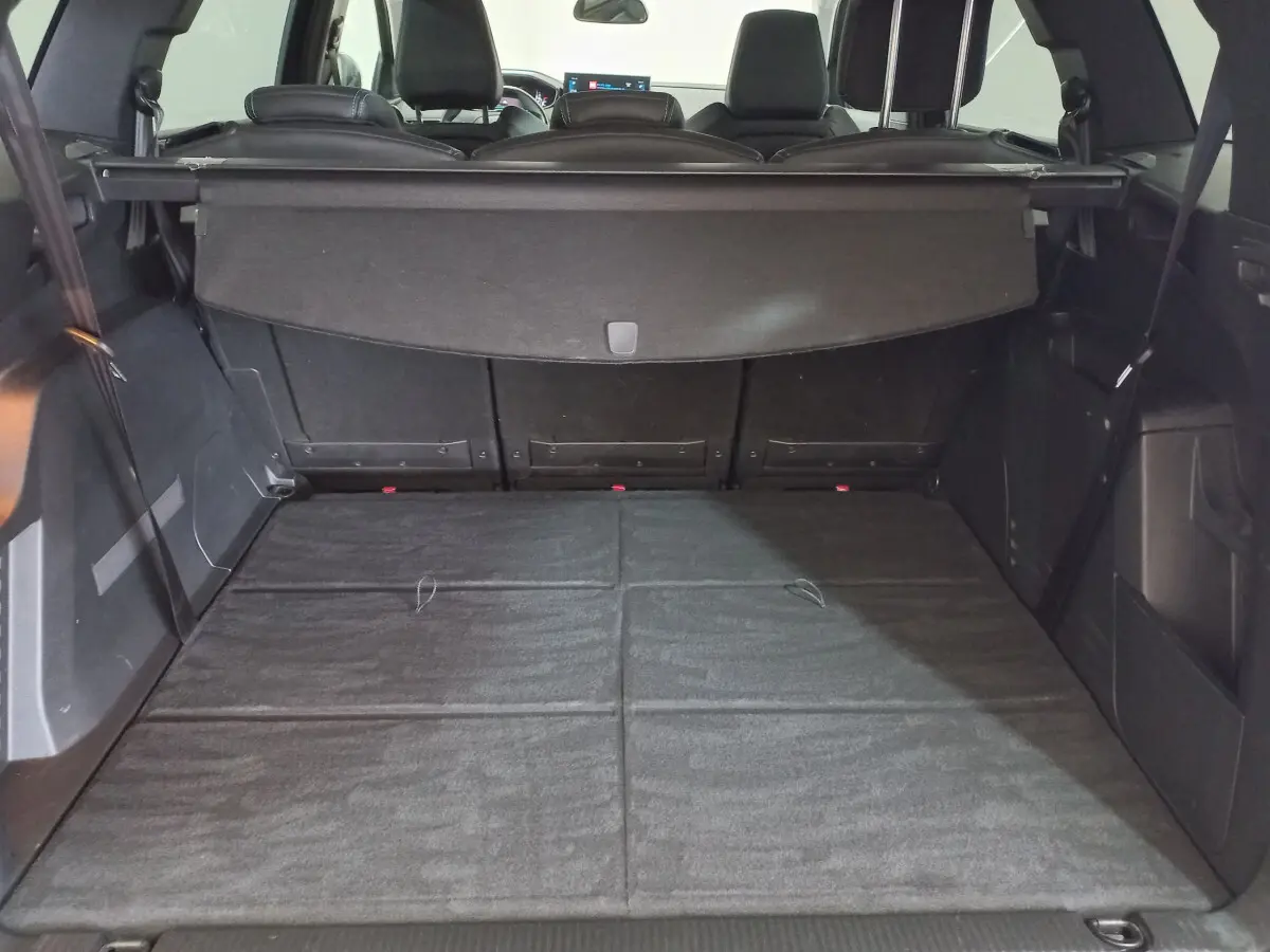 Coffre spacieux de Peugeot 5008 gris foncé vu de l'arrière avec banquette arrière rabattue et cache-bagages déployé.