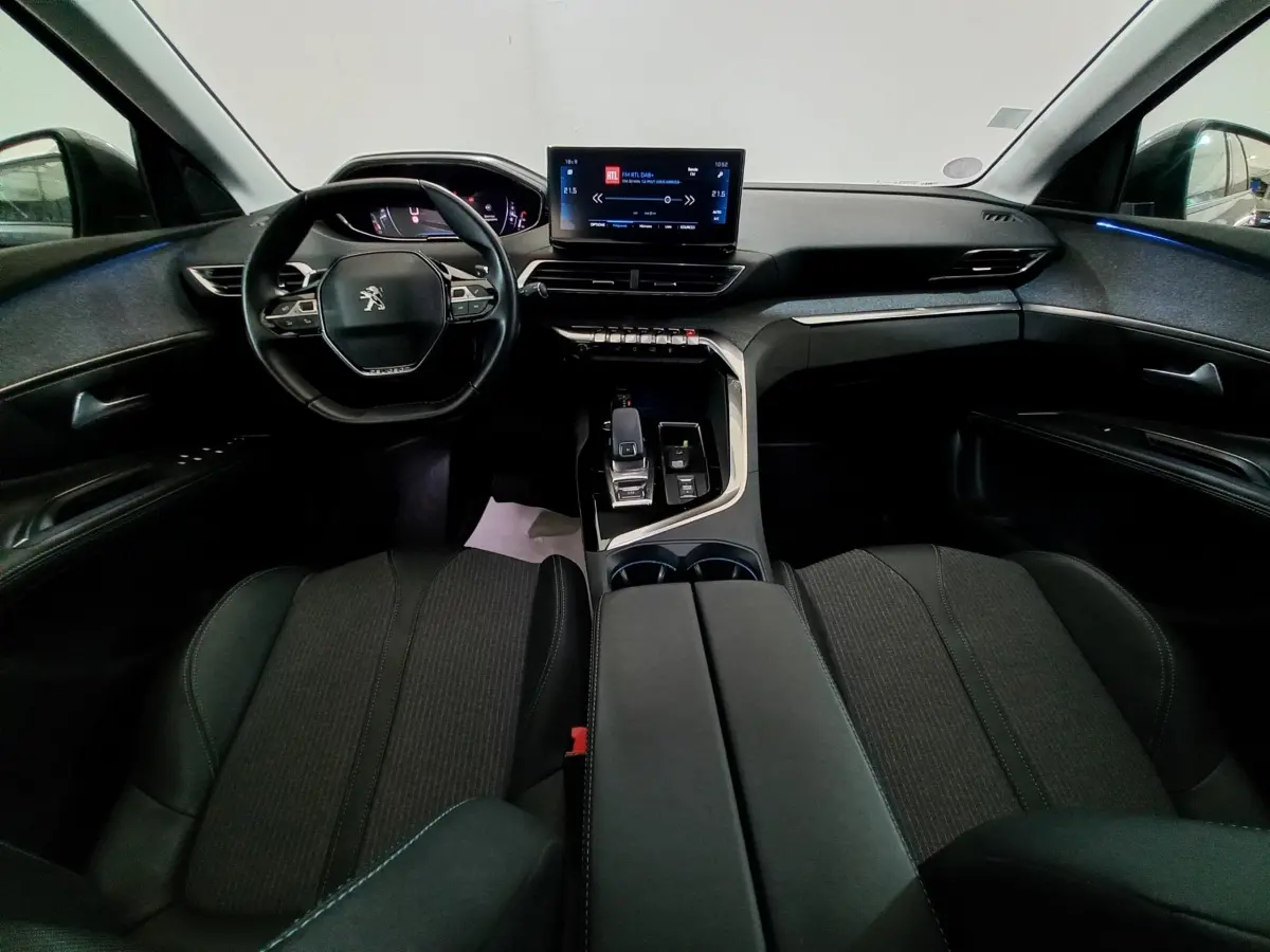 Vue intérieure avant du Peugeot 5008 2021 avec tableau de bord noir, volant compact et écran tactile central lumineux.