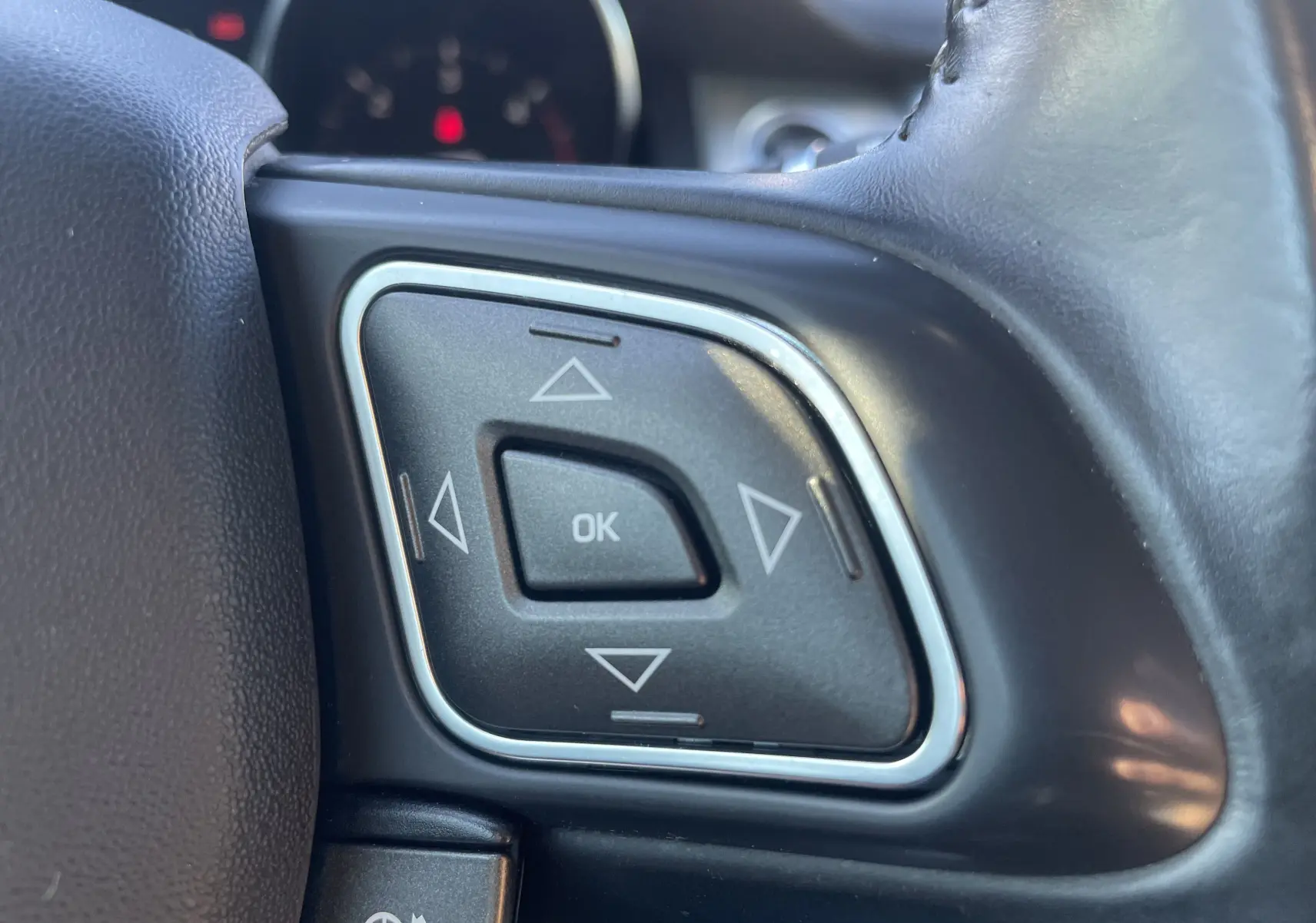 Gros plan sur les commandes multifonctions noires avec cadre chromé du volant d’un Range Rover Evoque 2016 noir.