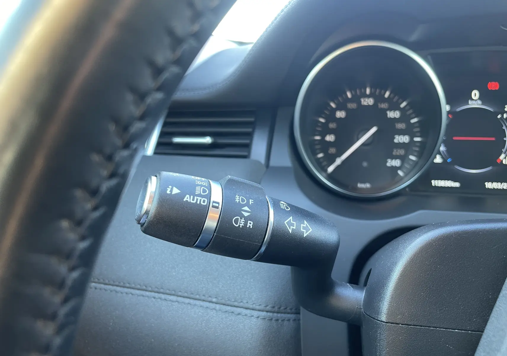 Gros plan sur la manette de clignotants noire du Range Rover Evoque 2016, avec tableau de bord et compteur en arrière-plan.