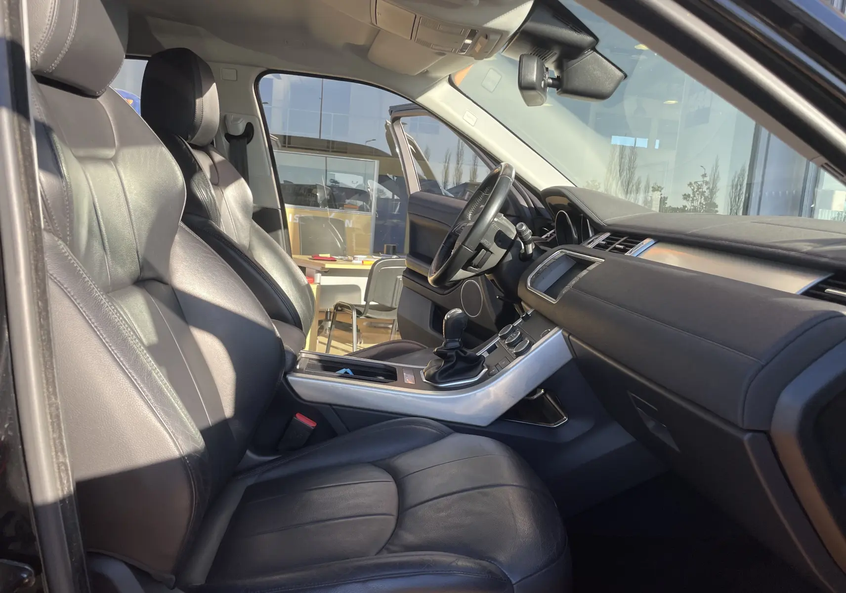 Intérieur noir cuir du Range Rover Evoque 2016, vue côté conducteur avec tableau de bord et levier de vitesses manuel.