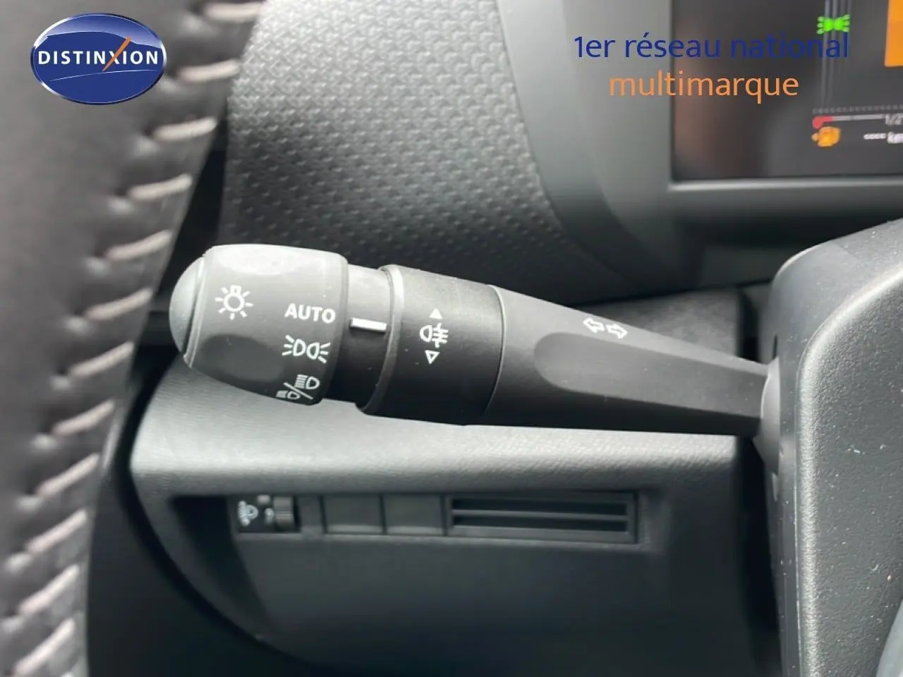 Gros plan sur la commande des phares et clignotants à gauche du volant dans l’habitacle noir d’une Citroën C4 blanche.
