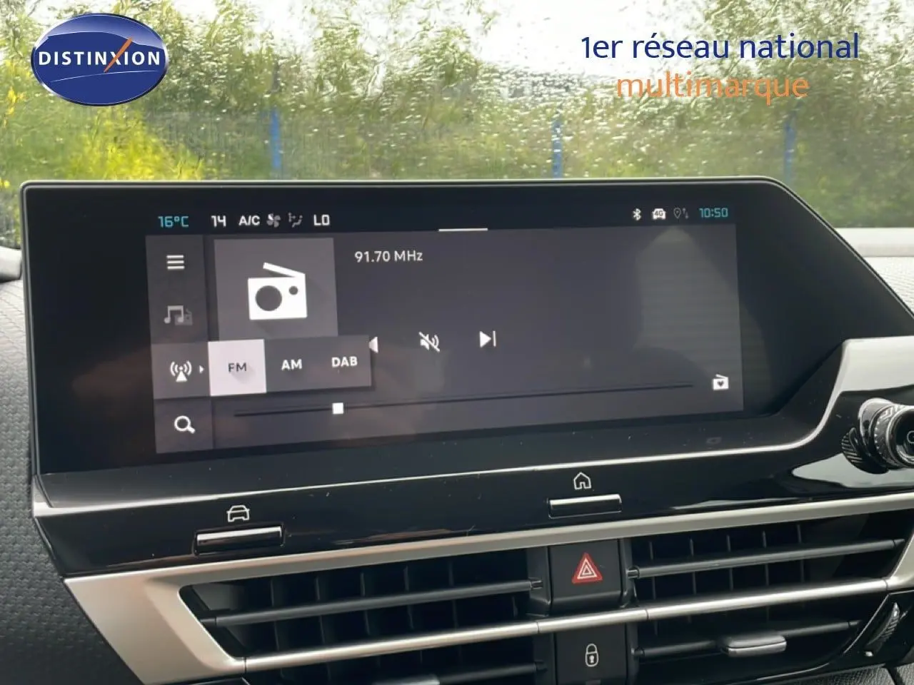 Écran tactile central du tableau de bord de la Citroën C4 blanc métal, affichant la radio FM à 91,7 MHz.