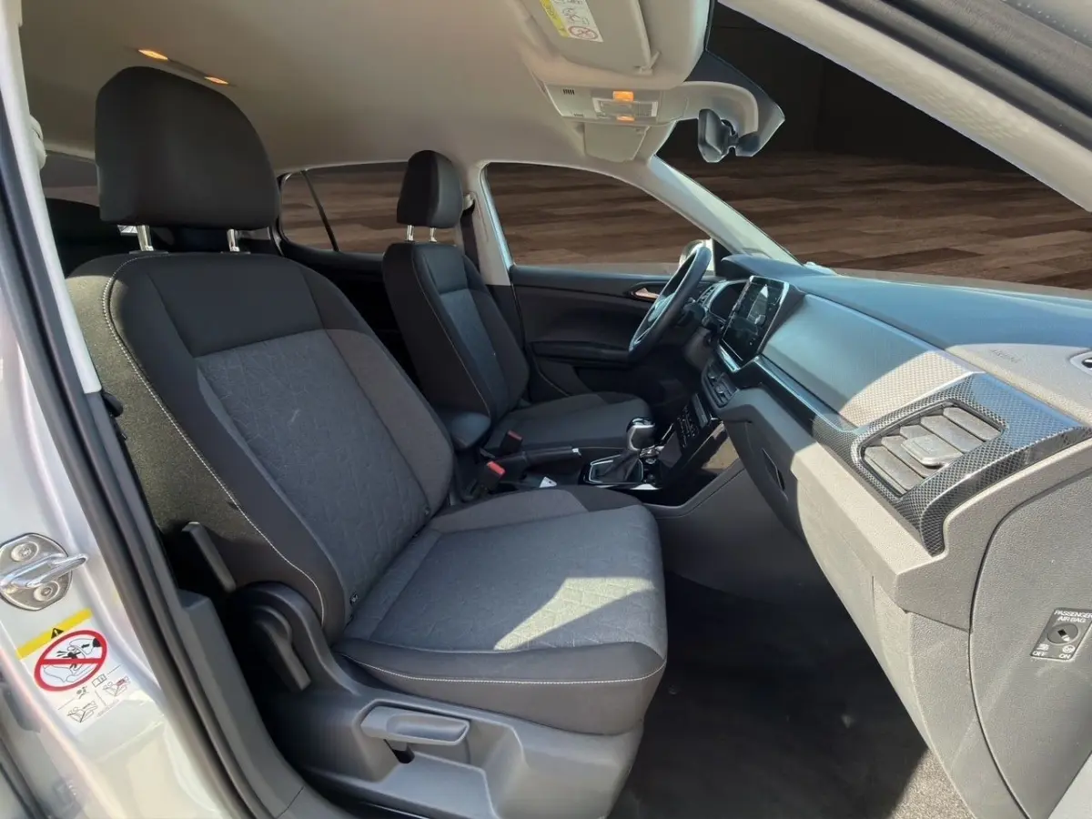 Vue intérieure côté droit du Volkswagen T-Cross gris clair 2025, montrant les sièges avant et le tableau de bord.