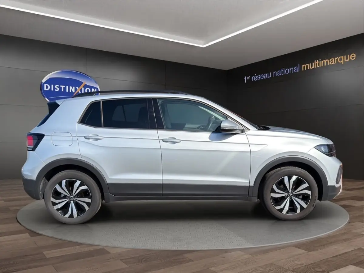 Vue latérale droite d'un Volkswagen T-Cross gris clair 2025 avec jantes alliage bicolores et toit noir.