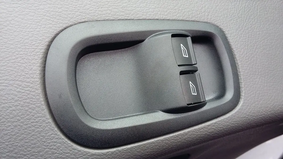 Gros plan sur les commandes électriques des vitres du côté conducteur du Ford Transit Fourgon blanc glacier 2022.