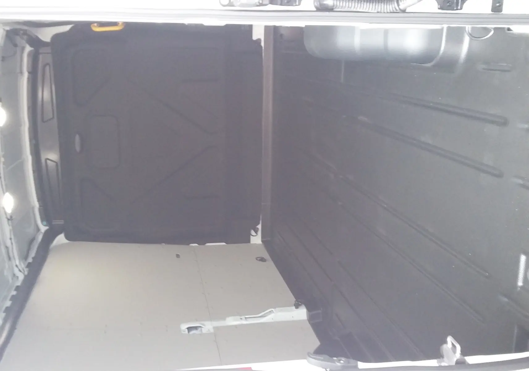 Intérieur du fourgon Ford Transit T350 blanc glacier, vue de l'espace de chargement vide avec parois latérales et plancher protégés.