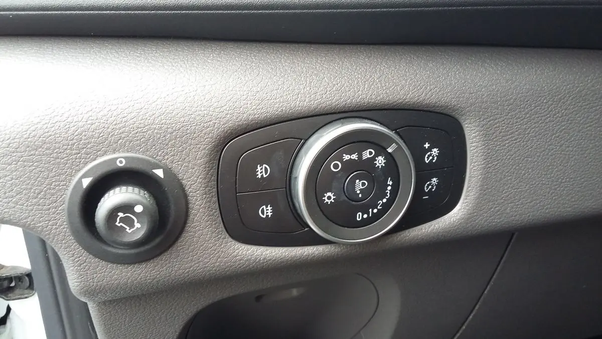 Gros plan sur les commandes d'éclairage et réglage des phares du Ford Transit Fourgon blanc Glacier 2022.