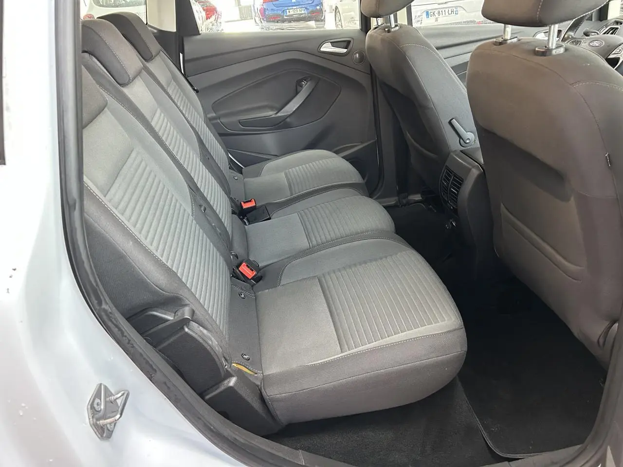 Vue intérieure côté gauche des sièges arrière gris d'une Ford C-MAX blanc 2018 avec portes ouvertes.