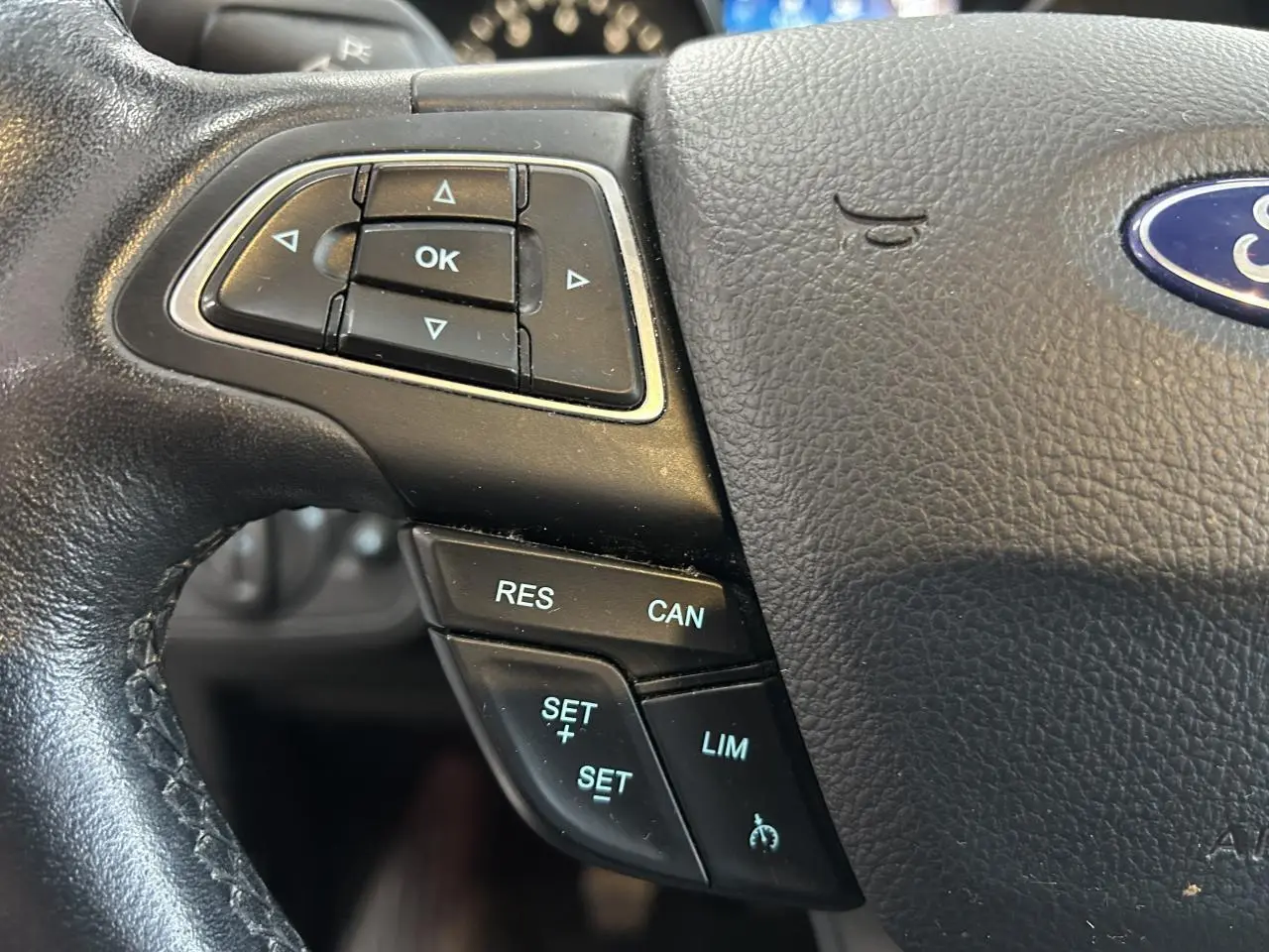 Gros plan sur le volant noir de la Ford C-MAX 2018, avec commandes de régulateur de vitesse et logo Ford visible.