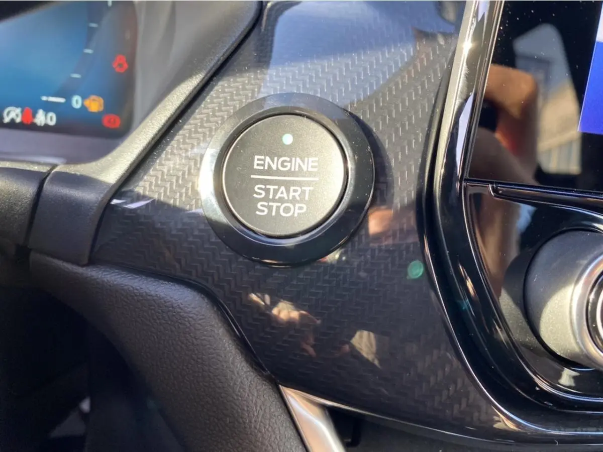Gros plan sur le bouton Engine Start Stop entouré d’un décor noir à effet carbone dans le tableau de bord d’une Ford Puma gris 2021.
