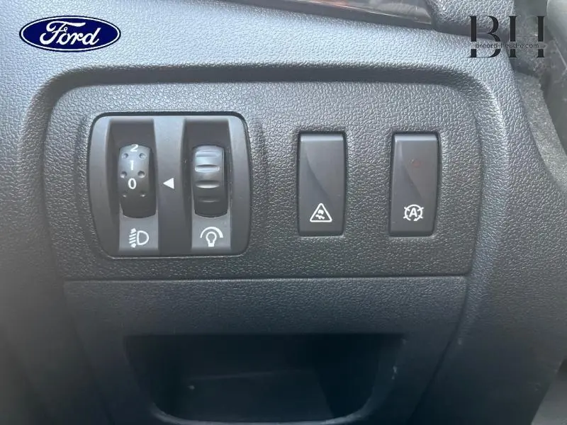 Gros plan sur les commandes de réglage des phares et système stop-start dans l'habitacle noir du Renault Grand Scenic noir étoilé.