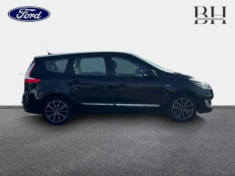 Profil côté gauche d'un Renault Grand Scenic noir étoilé, monospace 7 places avec jantes alliage et barres de toit.