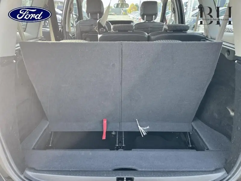 Coffre ouvert vu de l'arrière d'un Renault Grand Scenic noir étoilé avec sièges arrière relevés et rangements visibles.