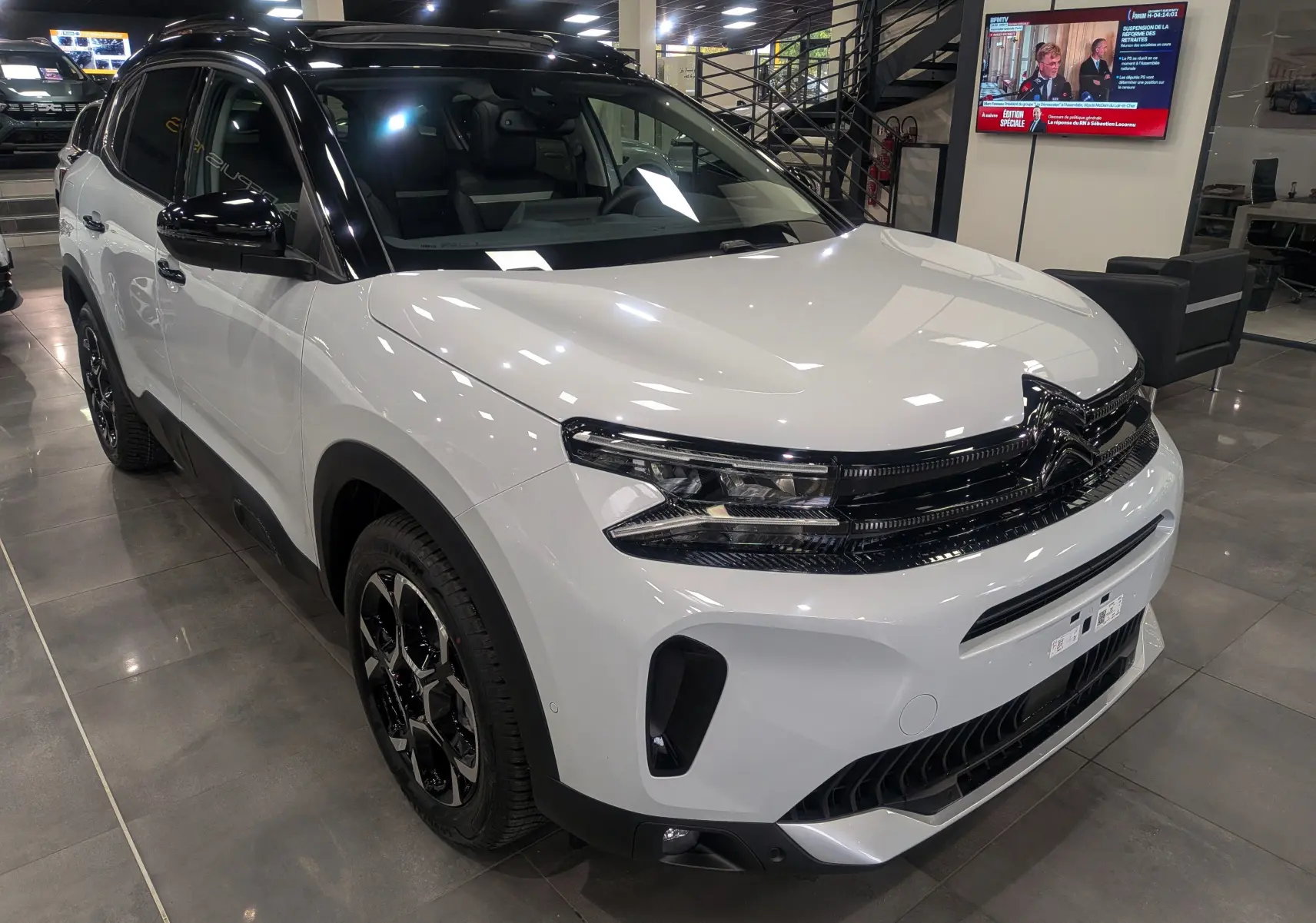 Citroën C5 Aircross hybride blanc Okénite avec toit noir, vue 3/4 avant en intérieur showroom.
