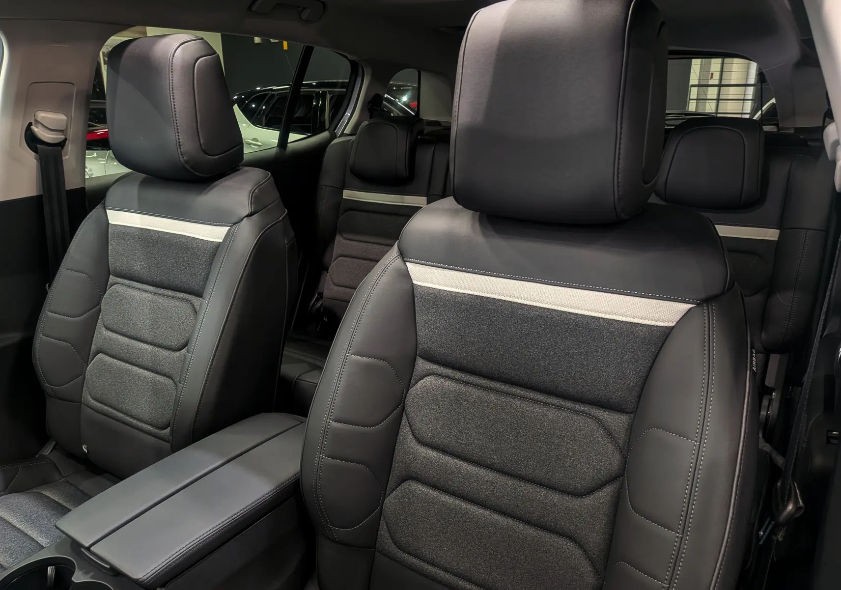 Gros plan sur les sièges avant en cuir noir et tissu gris du Citroën C5 Aircross hybride 2025, intérieur spacieux et moderne.