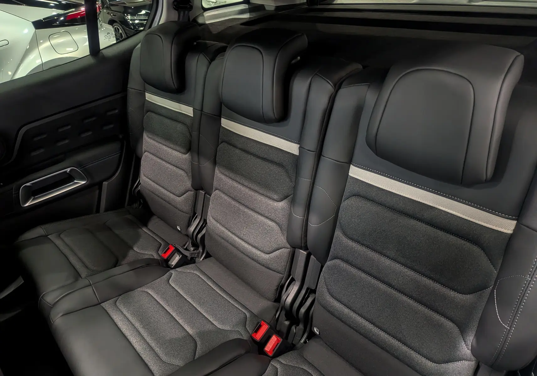 Vue intérieure sur la banquette arrière en cuir noir et tissu gris du Citroën C5 Aircross hybride 2025.