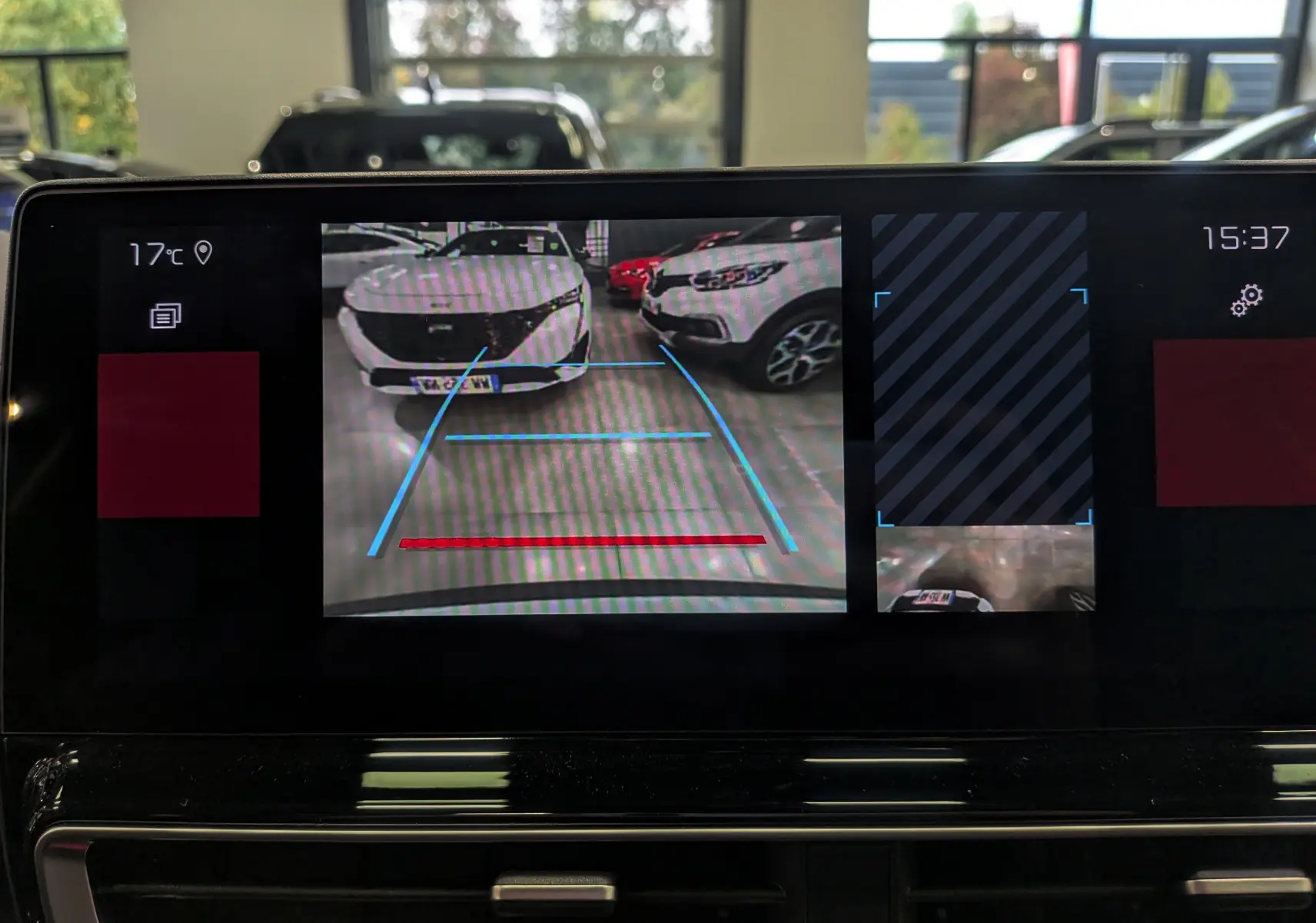 Affichage caméra de recul montrant une Citroën C5 Aircross blanche Okénite vue de face dans un parking intérieur.