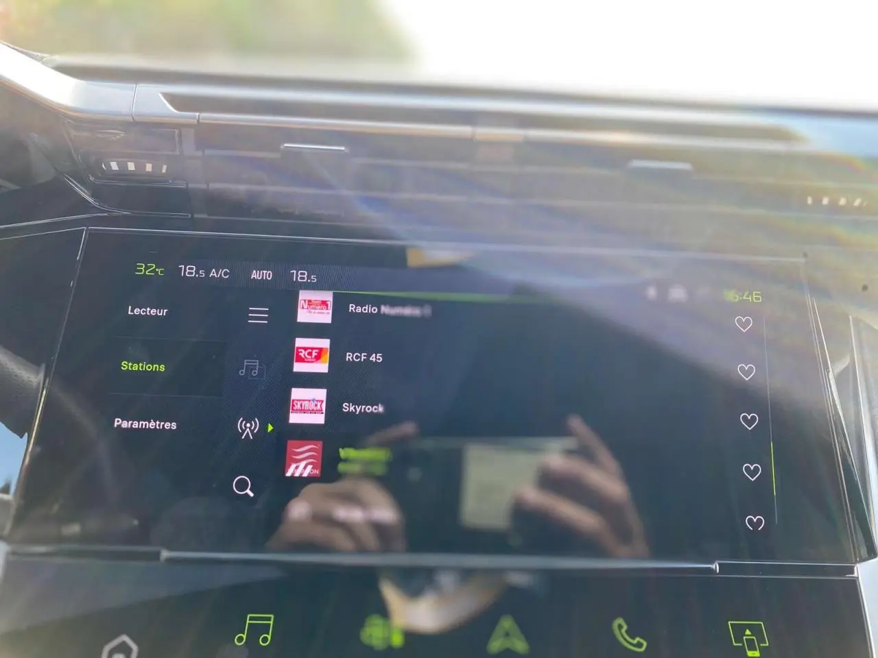 Écran tactile central de la Peugeot 308 Gris Selenium 2025 affichant les stations radio avec reflets du conducteur.