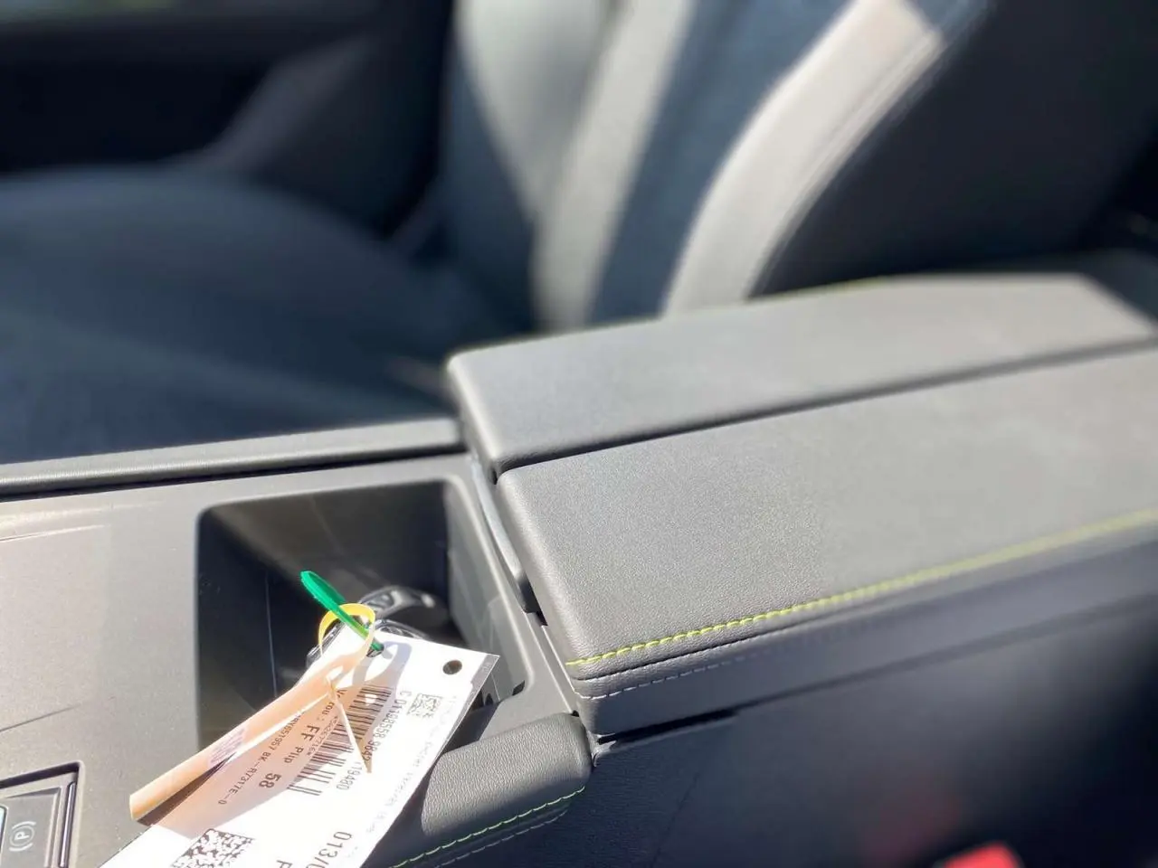 Gros plan sur l'accoudoir central gris de la Peugeot 308 GT 2025 avec clé et étiquette posées dessus.