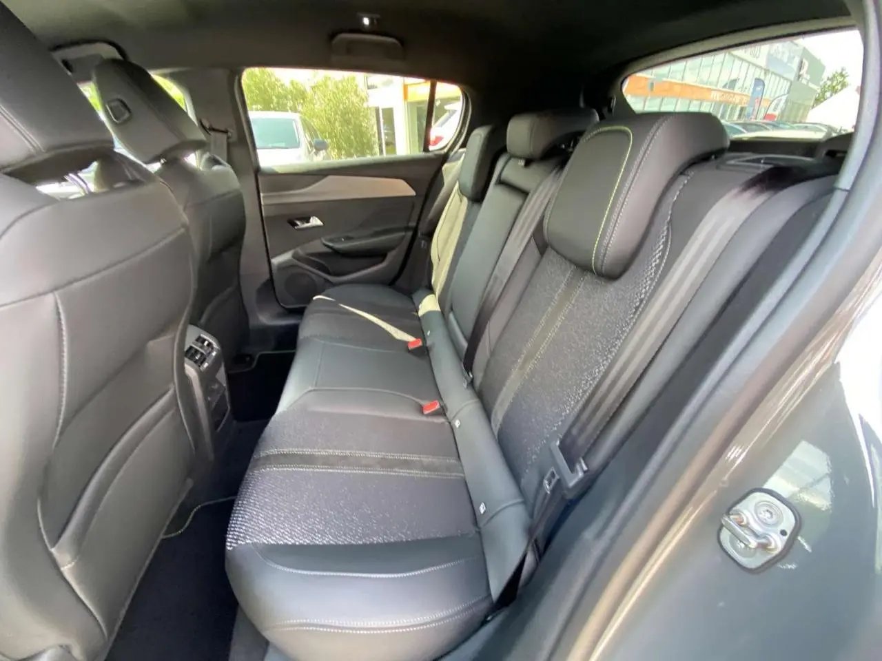 Vue intérieure côté droit des sièges arrière en cuir noir avec surpiqûres vertes d'une Peugeot 308 GT 2025 gris selenium.