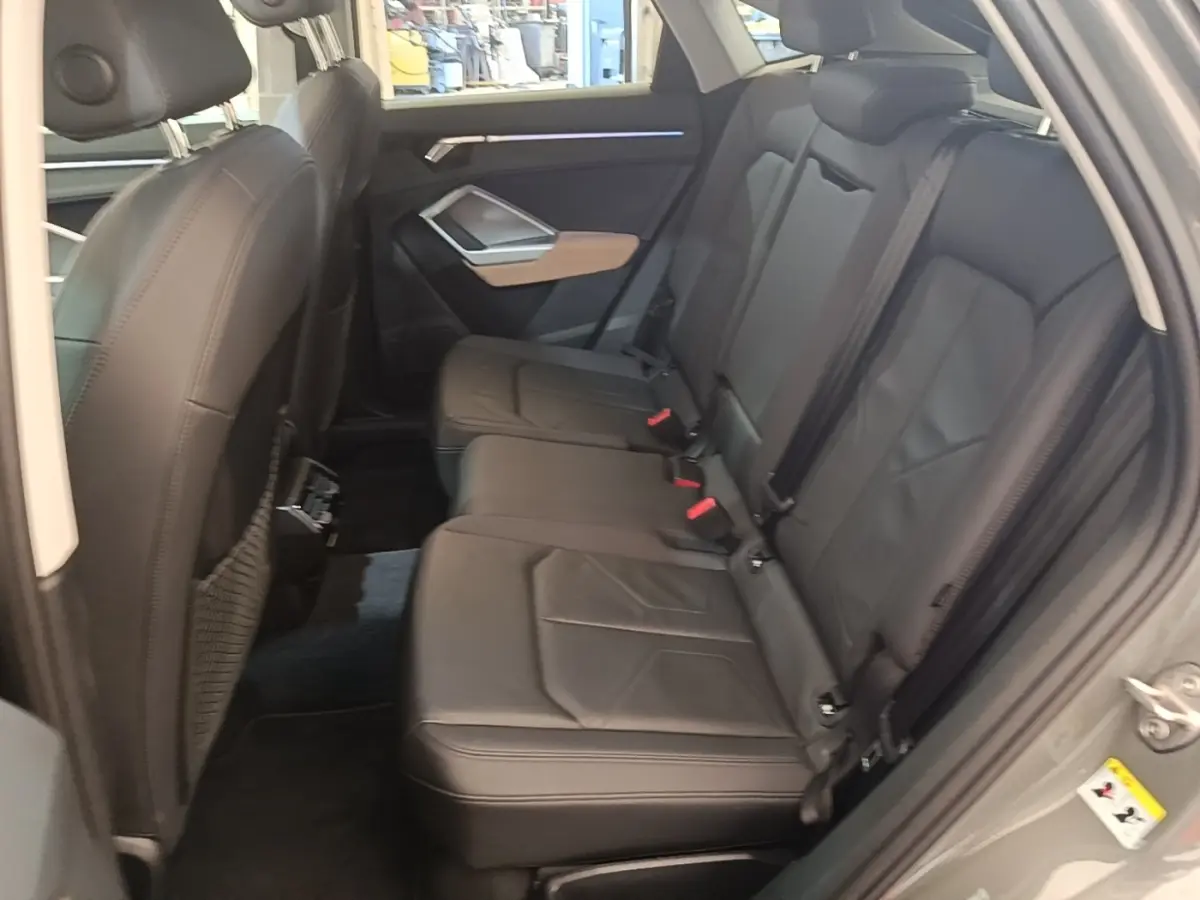 Vue intérieure côté droit des sièges arrière noirs en cuir de l'Audi Q3 Sportback 2024 avec banquette 3 places rabattables.