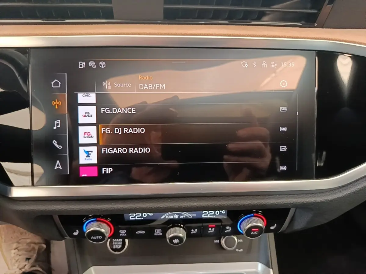 Gros plan sur l’écran tactile central affichant les radios DAB/FM dans l’Audi Q3 Sportback 2024 hybride rechargeable.