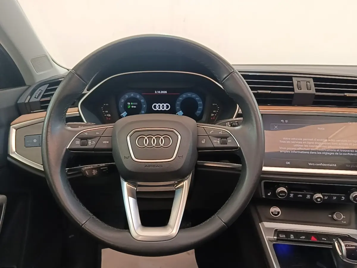 Vue intérieure centrée sur le volant cuir noir et le tableau de bord numérique de l'Audi Q3 Sportback 2024.